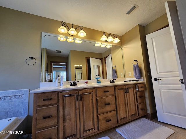 bathroom with vanity, a textured ceiling, a tub to relax in, and tile patterned floors