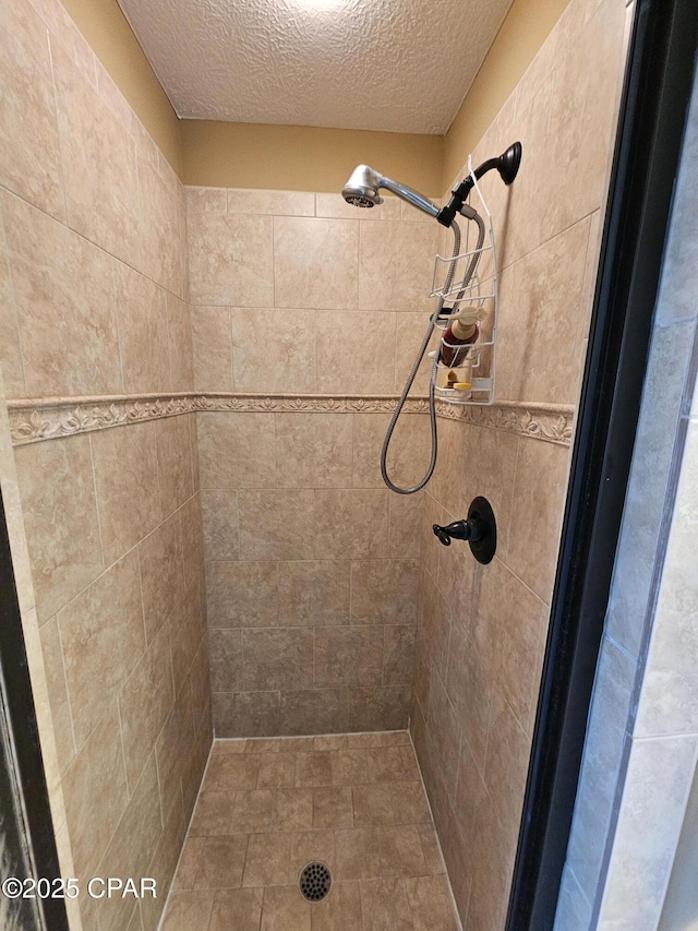 bathroom with tiled shower and a textured ceiling