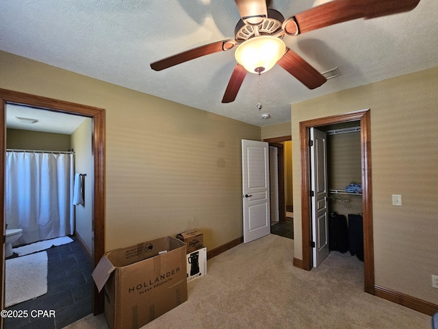 bedroom featuring a textured ceiling, ceiling fan, carpet floors, and a walk in closet