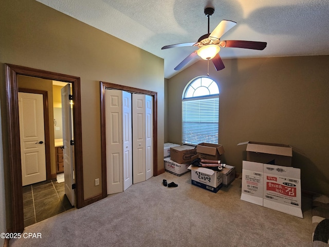 carpeted bedroom with a textured ceiling, a closet, vaulted ceiling, and ceiling fan