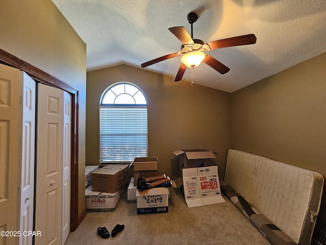 interior space featuring a textured ceiling, light carpet, lofted ceiling, and ceiling fan