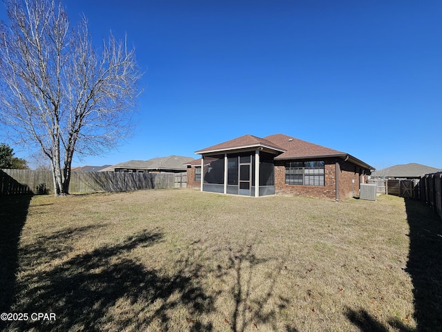 rear view of house featuring a lawn, a sunroom, and central AC