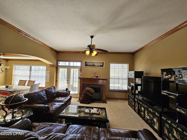 living room featuring a fireplace, ceiling fan, a textured ceiling, light carpet, and crown molding