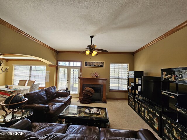 4408 Bylsma Cir, Panama City, FL 32404 - carpeted living room with a ceiling fan, a textured ceiling, a tile fireplace, arched walkways, and plenty of natural light