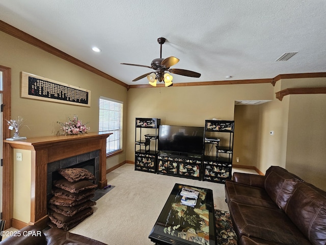 carpeted living room featuring ceiling fan, ornamental molding, a textured ceiling, and a tiled fireplace