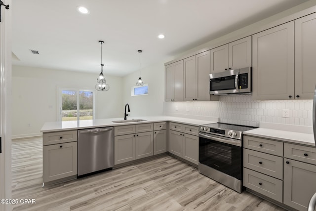 kitchen with appliances with stainless steel finishes, decorative light fixtures, light countertops, gray cabinetry, and a sink