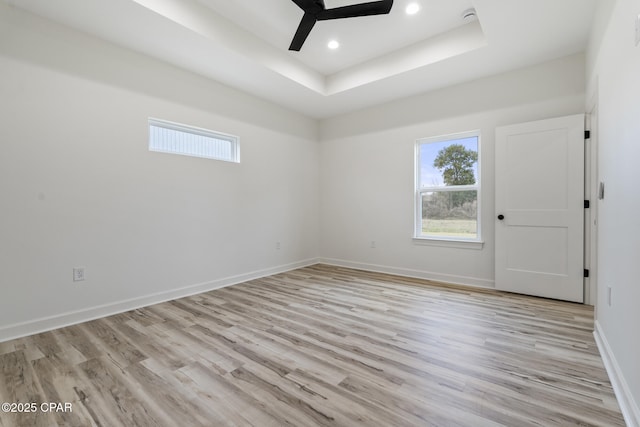 unfurnished room with light wood finished floors, baseboards, a raised ceiling, ceiling fan, and recessed lighting