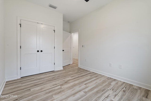 unfurnished bedroom with a closet, light wood-type flooring, visible vents, and baseboards