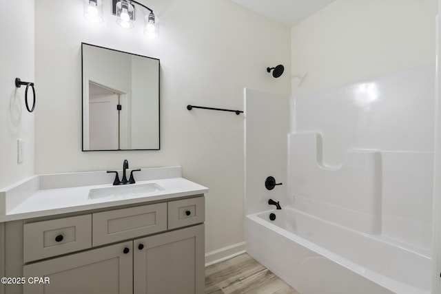 full bath with washtub / shower combination, vanity, baseboards, and wood finished floors