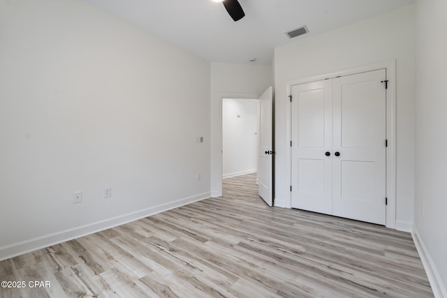 unfurnished bedroom featuring light wood finished floors, a closet, visible vents, and baseboards