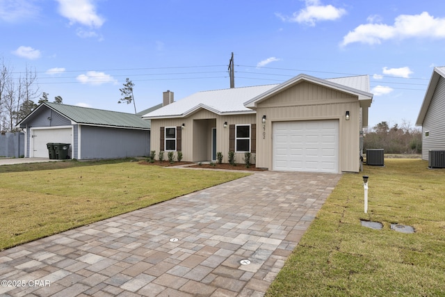 view of front of home with an attached garage, metal roof, decorative driveway, and a front yard