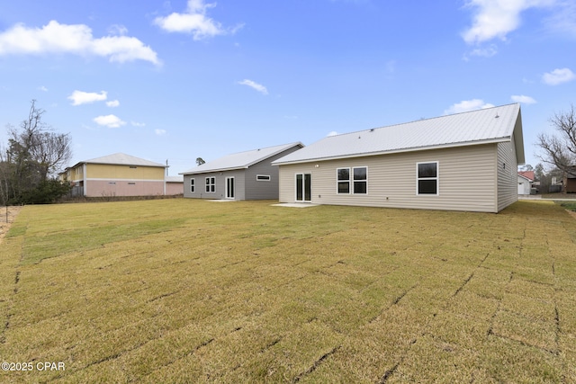 back of property with metal roof and a yard