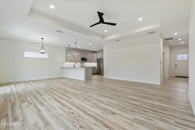 unfurnished living room with baseboards, visible vents, and a raised ceiling