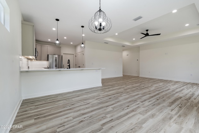 unfurnished living room with ceiling fan, a tray ceiling, visible vents, and recessed lighting