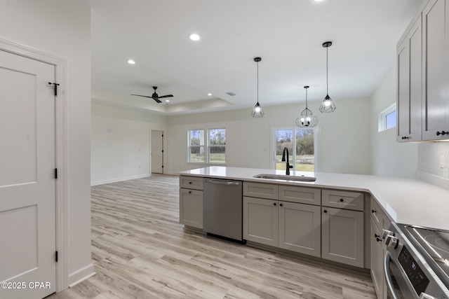 kitchen with pendant lighting, stainless steel appliances, gray cabinets, light countertops, and a sink