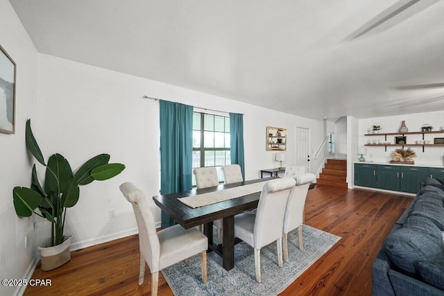 dining space with dark wood finished floors, stairway, and baseboards