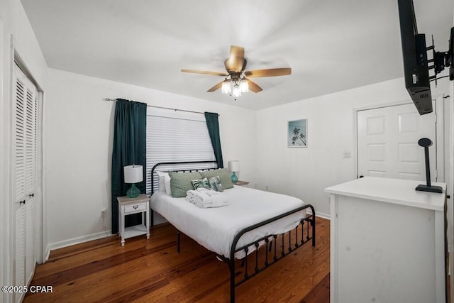 bedroom with a ceiling fan, baseboards, dark wood finished floors, and a closet