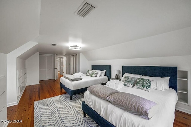 bedroom with dark wood-style floors, lofted ceiling, and visible vents