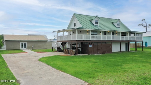 view of front of house with french doors, metal roof, driveway, a front lawn, and stairs