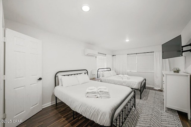 bedroom featuring a wall unit AC, dark wood-style floors, baseboards, and recessed lighting