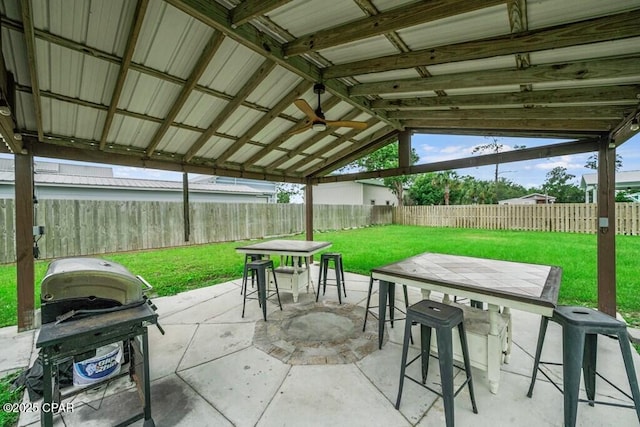 view of patio / terrace featuring outdoor dining area, area for grilling, ceiling fan, a bar, and a fenced backyard