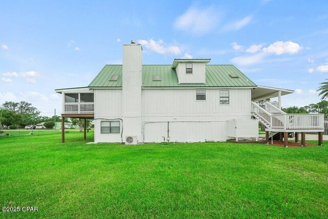 rear view of property with metal roof, a yard, stairway, and a sunroom