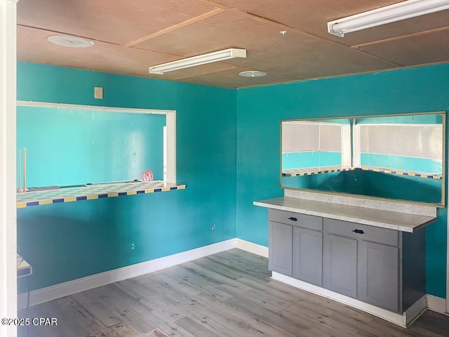 kitchen featuring light wood finished floors, gray cabinets, baseboards, and light countertops