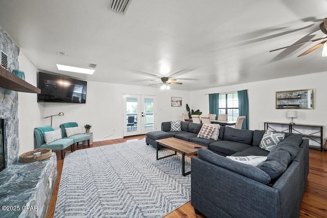 living area featuring ceiling fan, a fireplace, wood finished floors, and visible vents