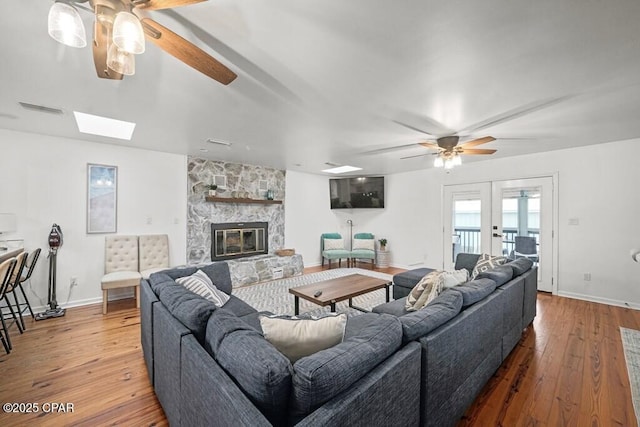 living room with a fireplace, wood finished floors, visible vents, baseboards, and french doors