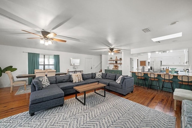 living room featuring a ceiling fan, stairway, visible vents, and light wood-style flooring