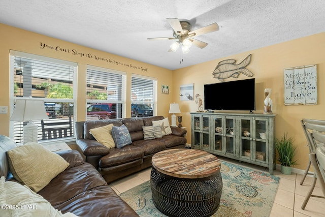 living room with ceiling fan, baseboards, a textured ceiling, and light tile patterned flooring