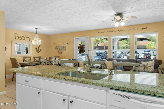 kitchen featuring light tile patterned flooring, a sink, white cabinets, open floor plan, and dishwasher