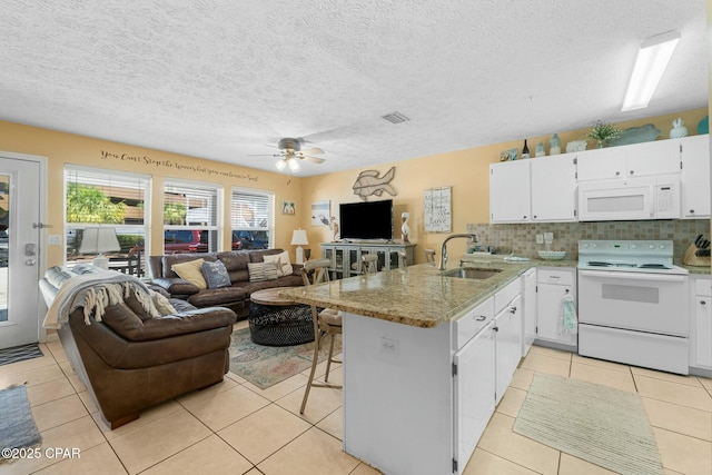 kitchen with a peninsula, white appliances, a sink, white cabinets, and open floor plan