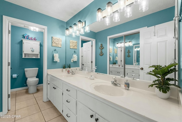 bathroom with toilet, tile patterned flooring, double vanity, and a sink