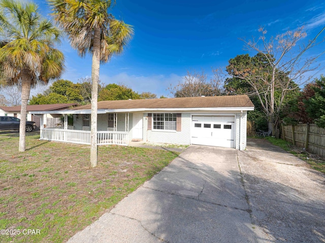 ranch-style home with concrete driveway, an attached garage, covered porch, a front lawn, and brick siding