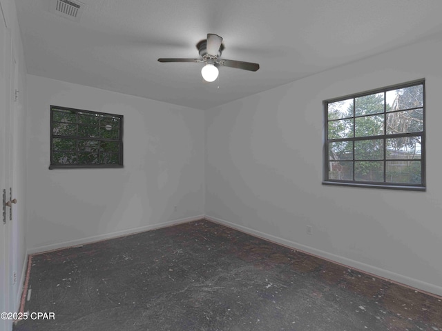 empty room with ceiling fan, concrete flooring, visible vents, and baseboards