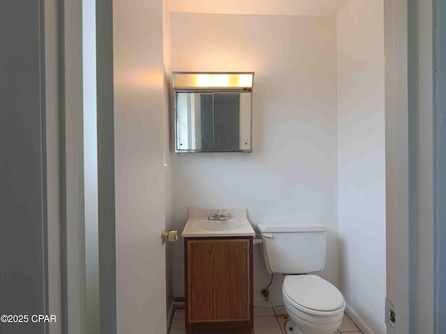 half bathroom with tile patterned flooring, vanity, and toilet