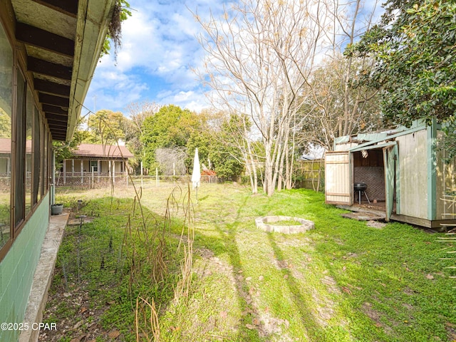 view of yard featuring fence, a fire pit, and an outdoor structure