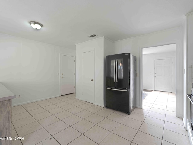 kitchen featuring light tile patterned flooring, baseboards, visible vents, and freestanding refrigerator