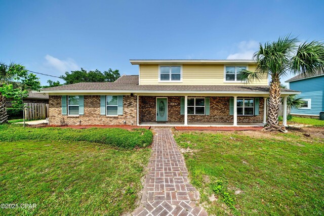 traditional-style home with roof with shingles, a front lawn, and brick siding