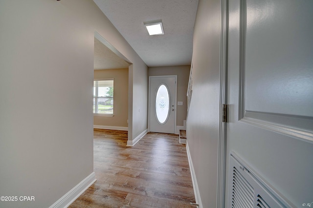 entryway featuring light wood-style floors, baseboards, and a textured ceiling