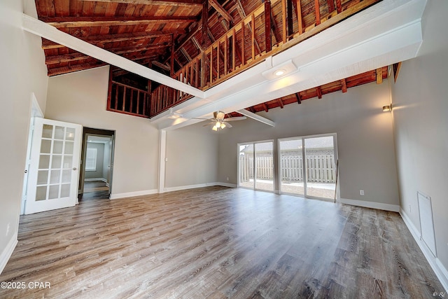 unfurnished living room with wooden ceiling, wood finished floors, beam ceiling, and baseboards