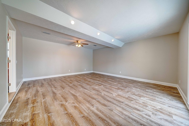 spare room featuring visible vents, light wood-style flooring, ceiling fan, a textured ceiling, and baseboards