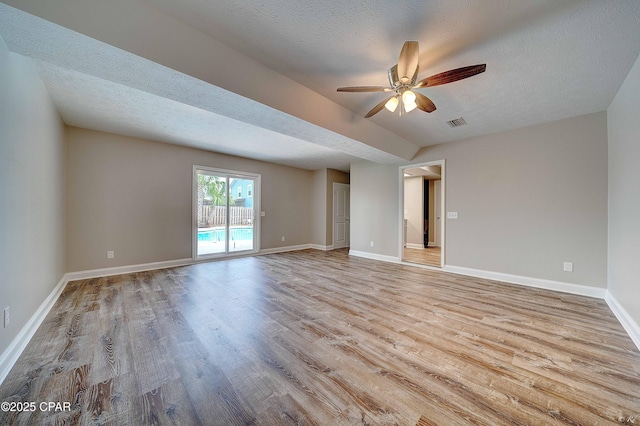 empty room featuring ceiling fan, a textured ceiling, visible vents, baseboards, and light wood finished floors