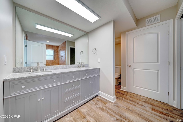 bathroom with toilet, visible vents, a sink, and wood finished floors