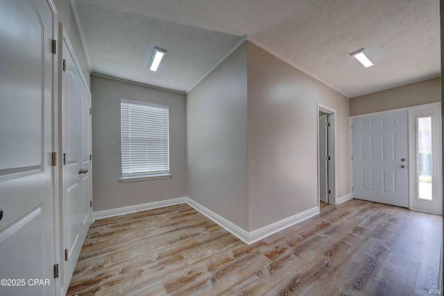 foyer entrance with light wood-type flooring, baseboards, and a textured ceiling