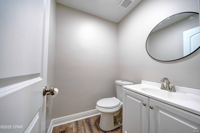 bathroom featuring baseboards, visible vents, toilet, wood finished floors, and vanity