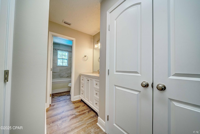 bathroom with visible vents, toilet, wood finished floors, a textured ceiling, and vanity