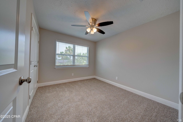 empty room featuring baseboards, a textured ceiling, a ceiling fan, and light colored carpet