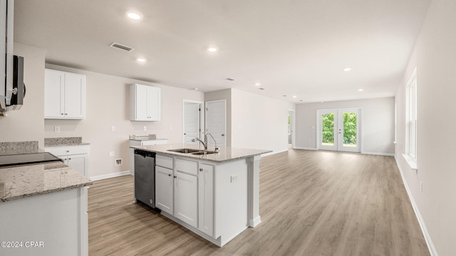 kitchen with light stone counters, a sink, white cabinets, stainless steel dishwasher, and light wood-type flooring